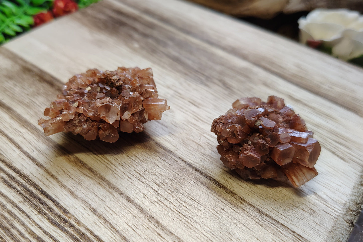 Two crystal formations on a wooden surface with a natural background