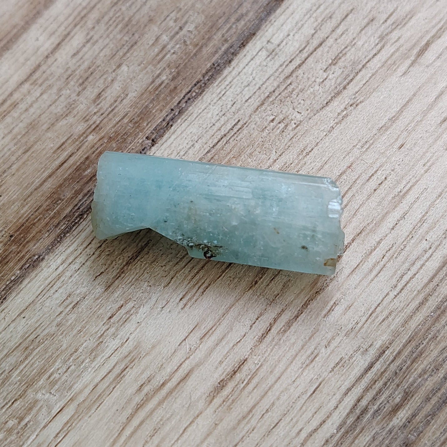 Small green stone on a wooden surface with a blurred background