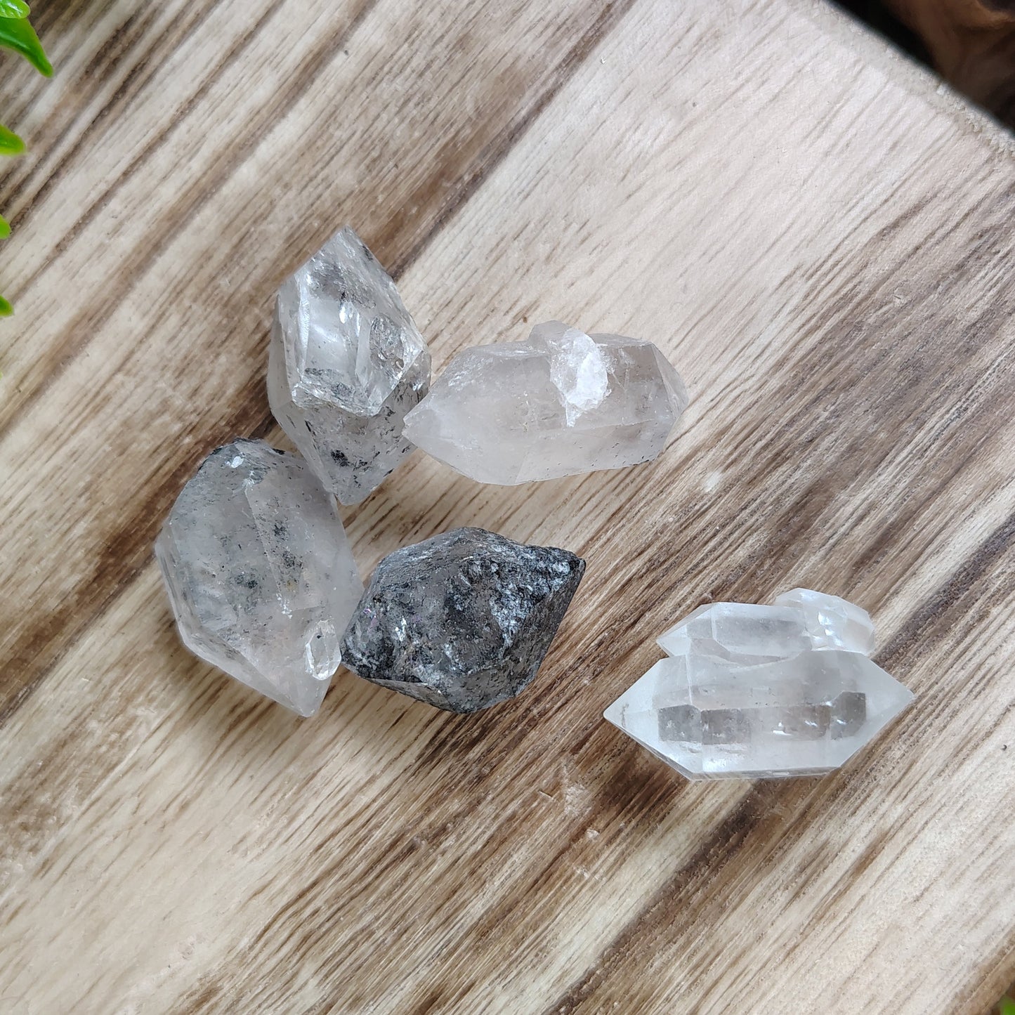 Crystal stones on a wooden surface with greenery around
