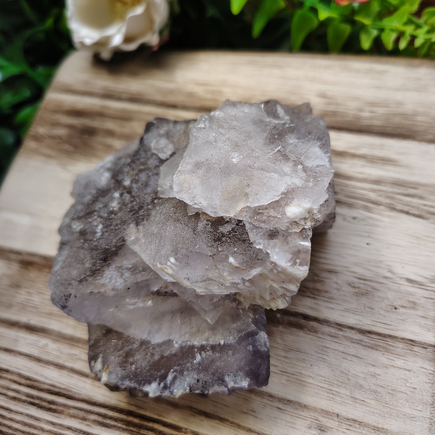 Crystal rock on a wooden surface with greenery in the background