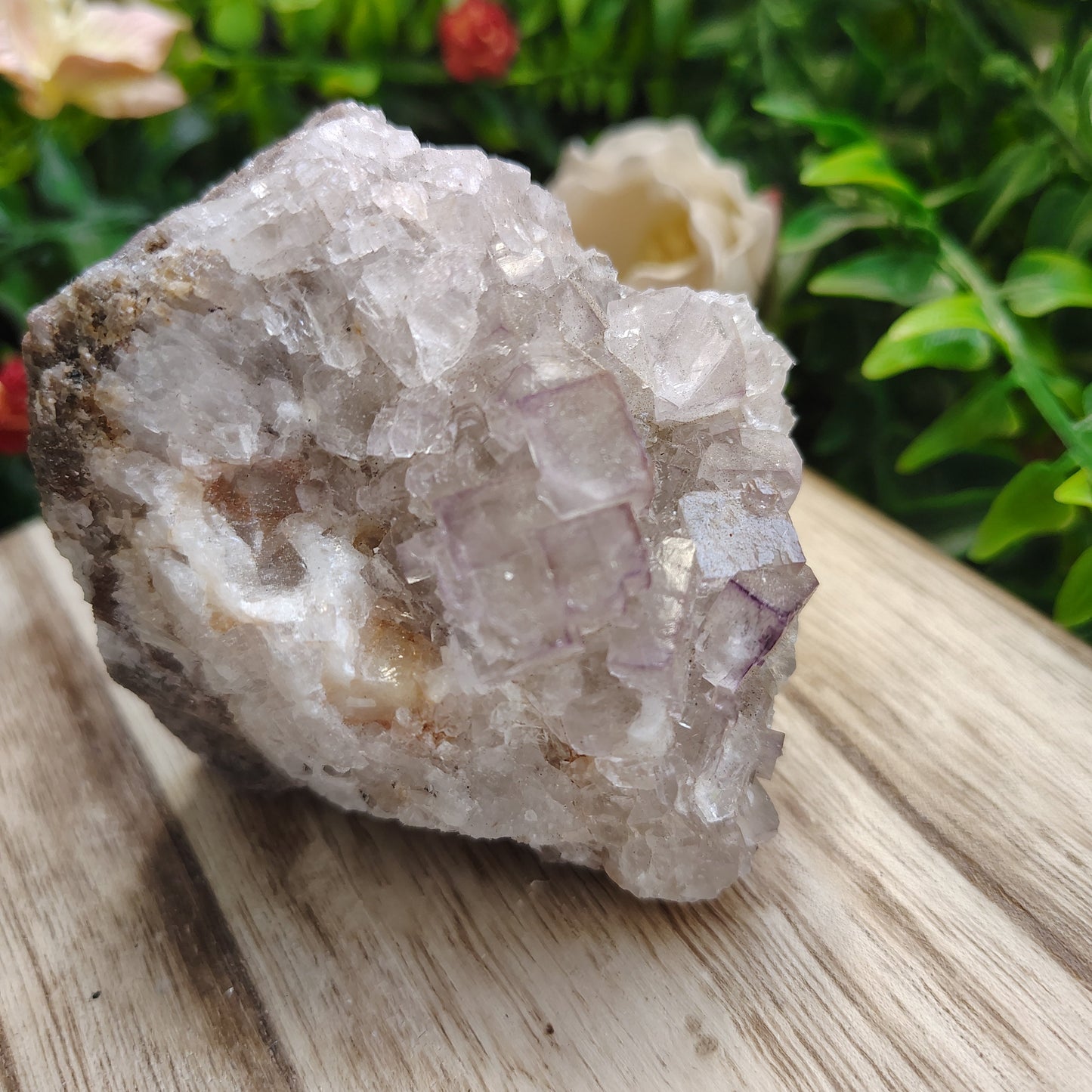 Crystal rock on a wooden surface with greenery in the background