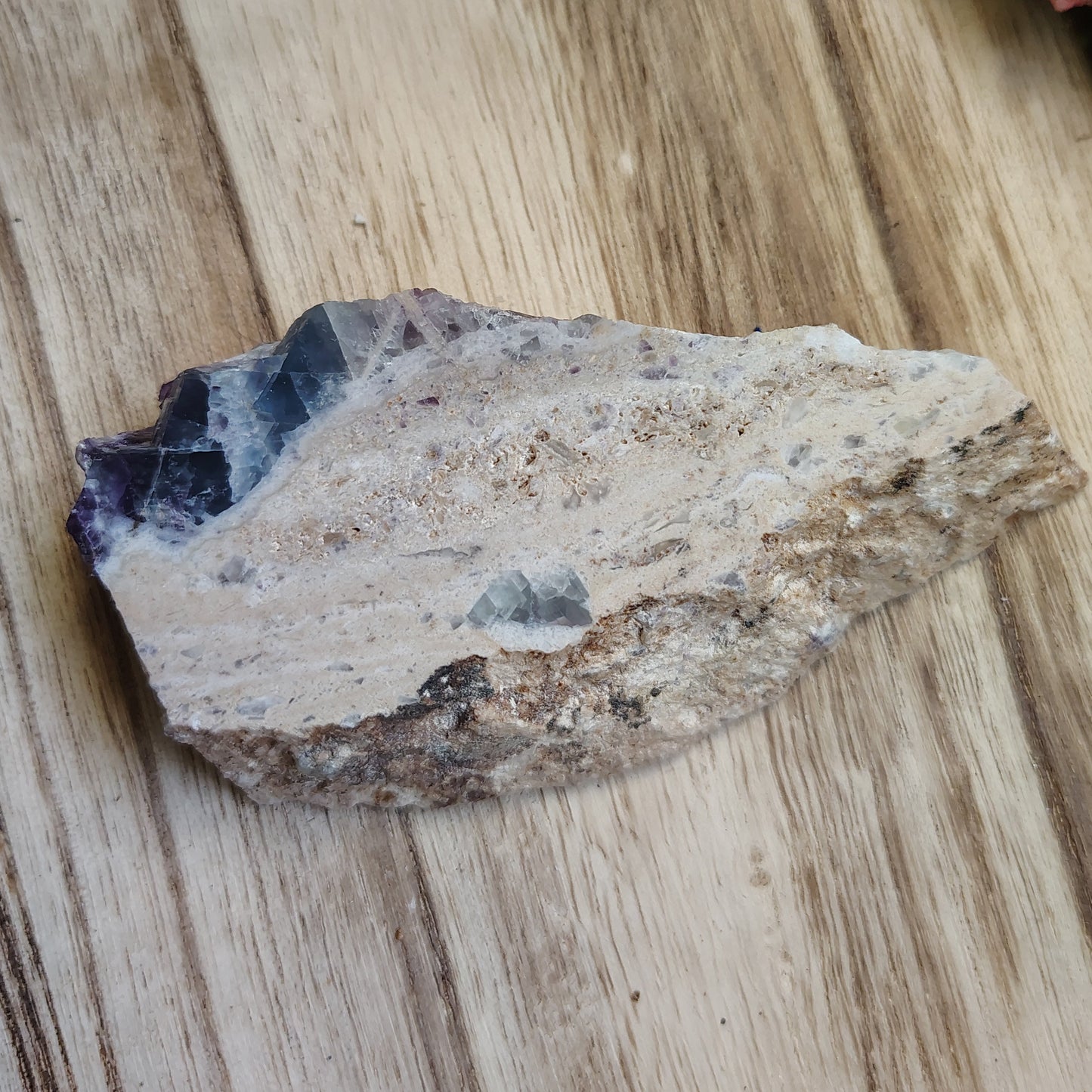 Mineral sample on a wooden surface with flowers in the background