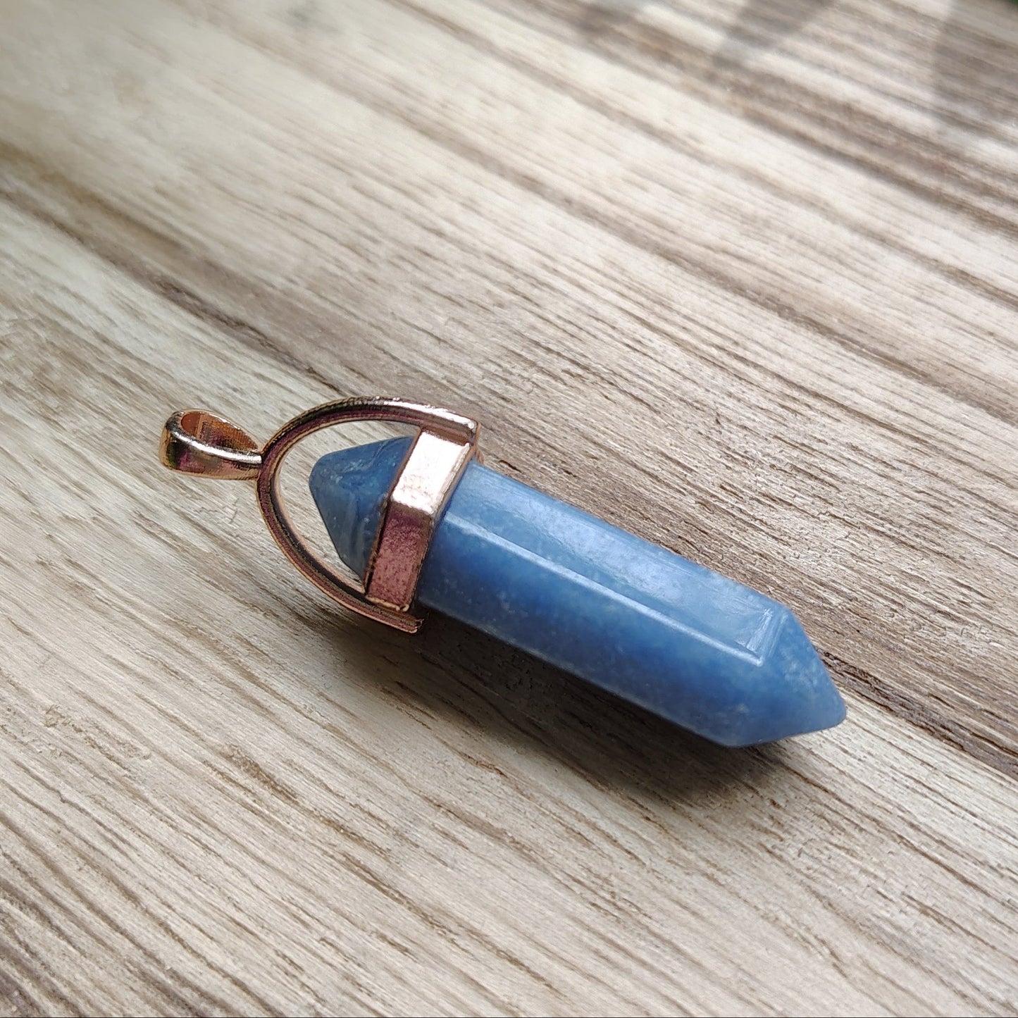Blue crystal on a wooden surface with green leaves in the background