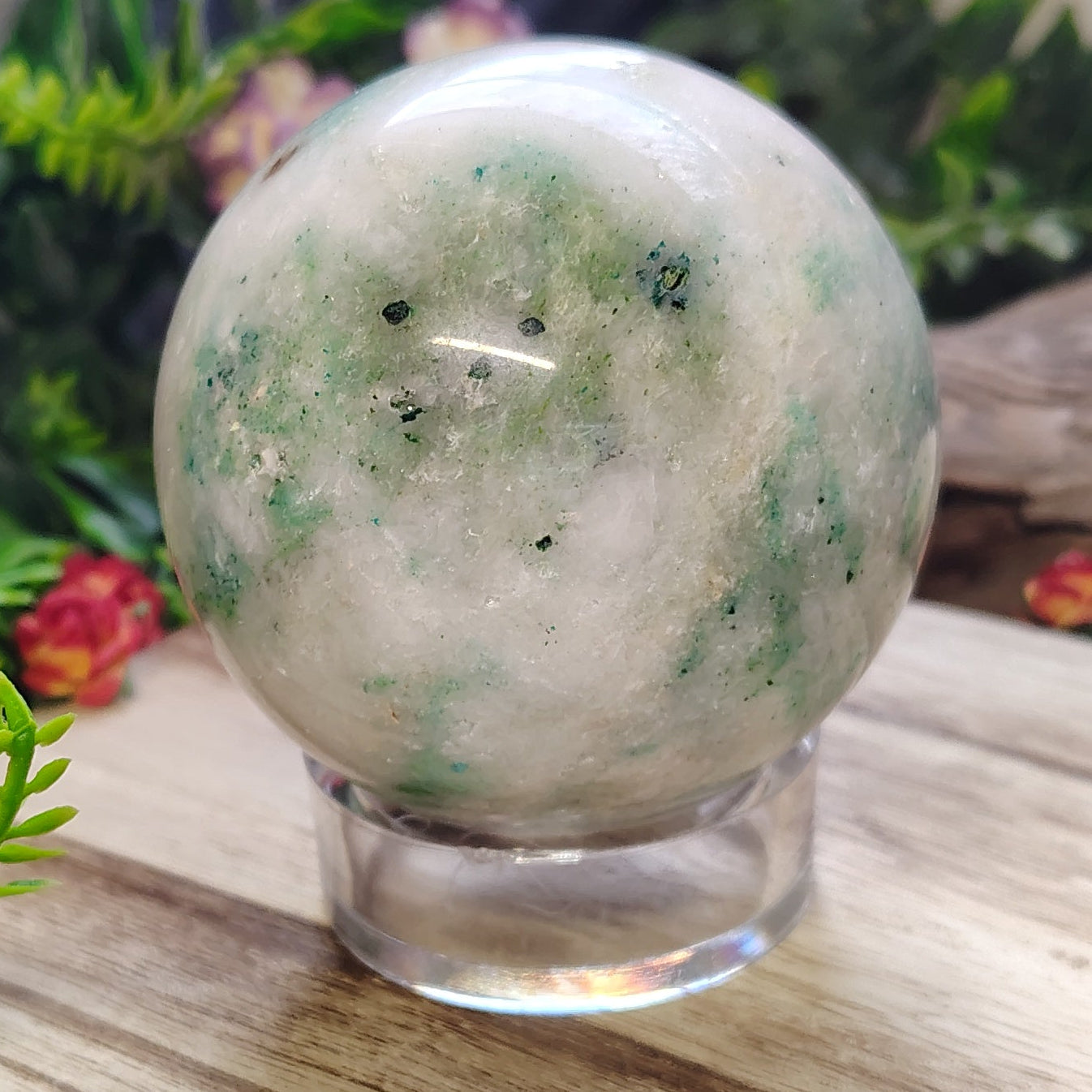 Crystal ball on a wooden surface with plants and flowers in the background