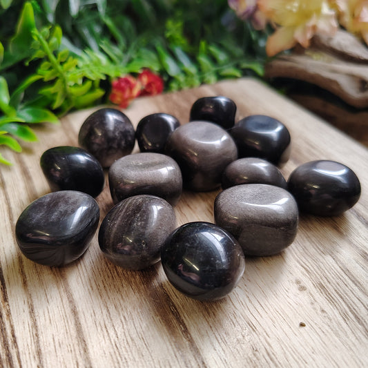 Black stones on a wooden surface with greenery in the background
