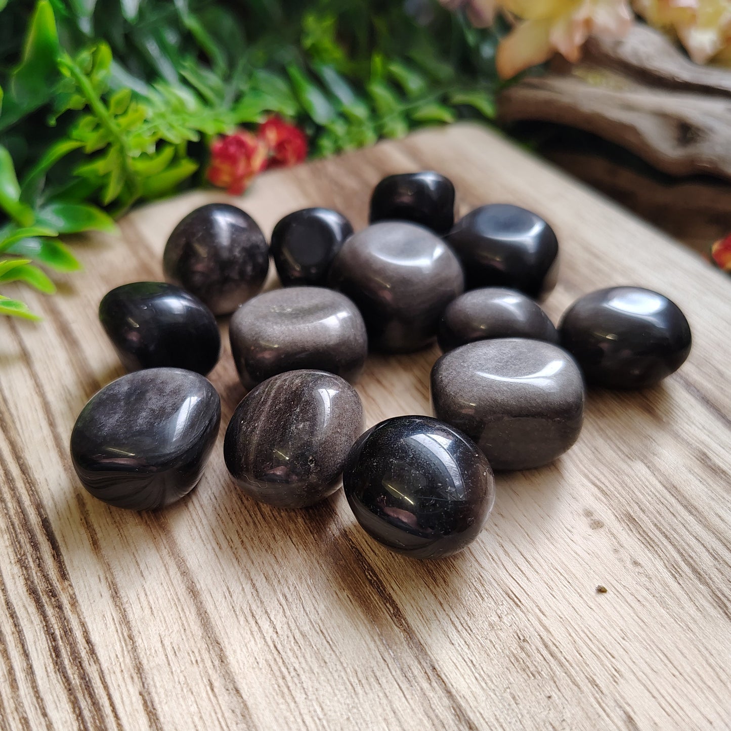 Black stones on a wooden surface with greenery in the background