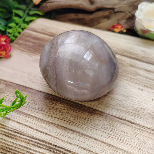 Crystal ball on a wooden surface with plants and flowers in the background