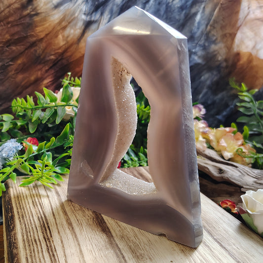 Crystal-like sculpture on a wooden surface with greenery in the background