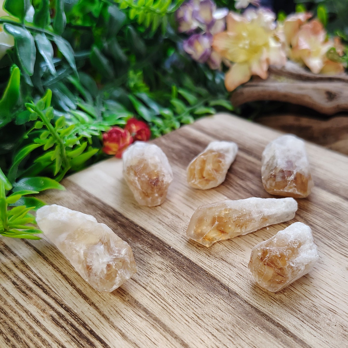 Citrines on a wooden surface with greenery and flowers in the background