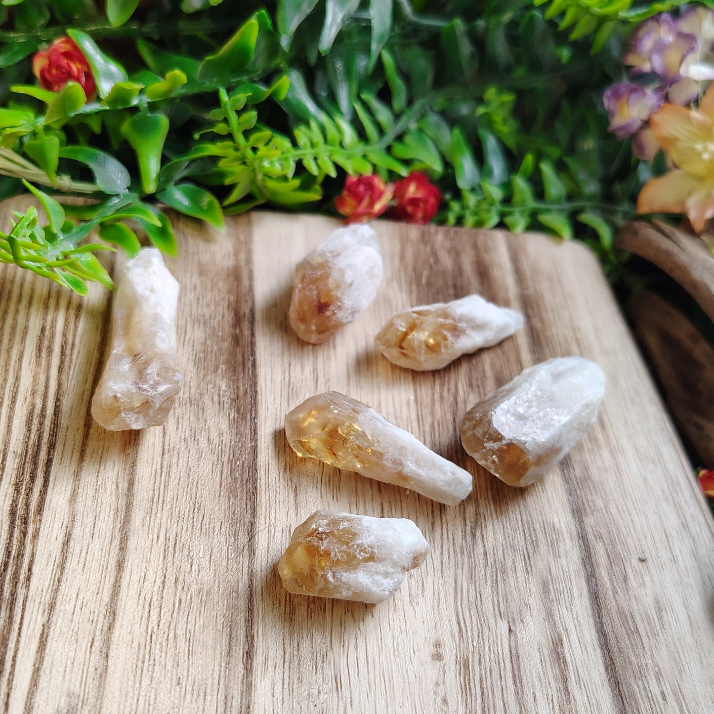 Citrines on a wooden surface with greenery and flowers in the background
