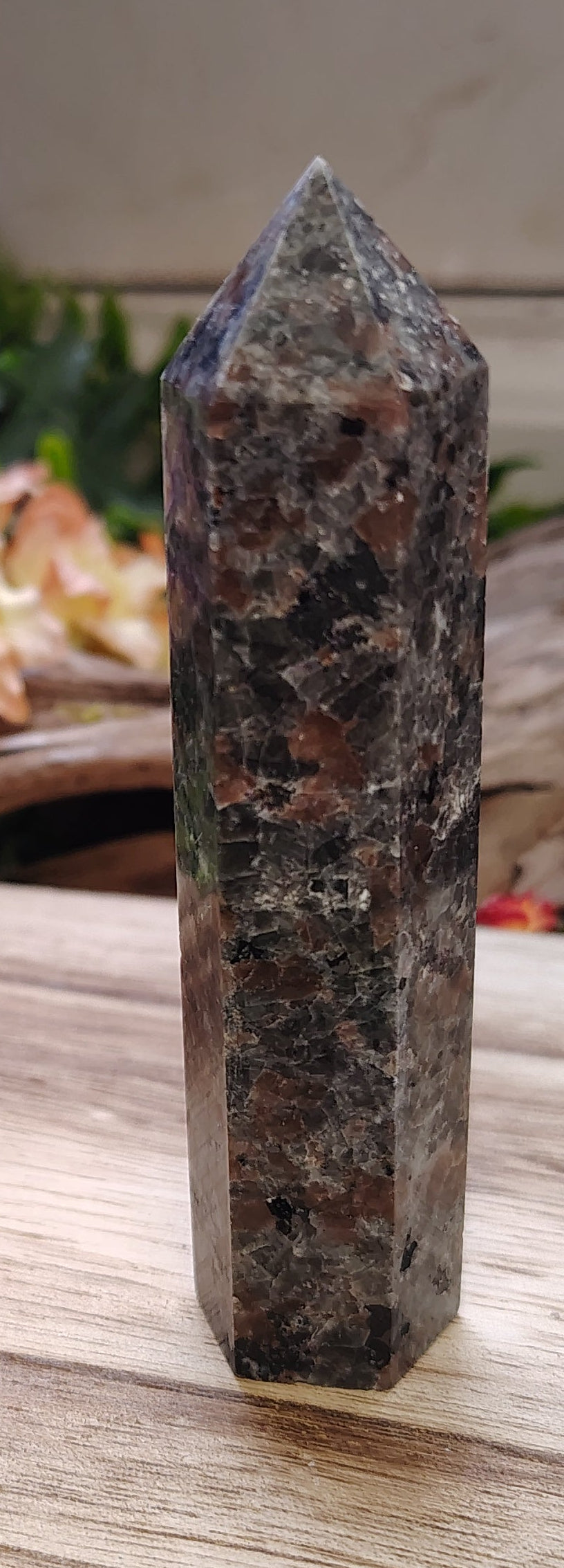 Crystal tower on a wooden surface with plants and flowers in the background
