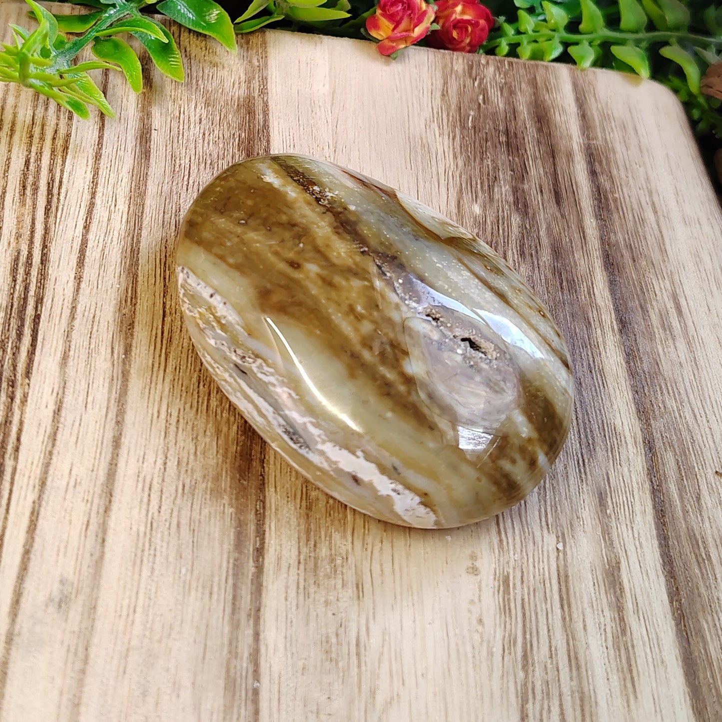 Crystal stone on a wooden surface with greenery and flowers