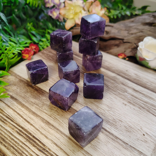 Amethyst crystals on a wooden surface with natural elements in the background