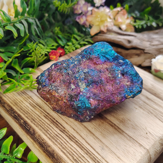 Colorful mineral stone on a wooden board with greenery and flowers in the background