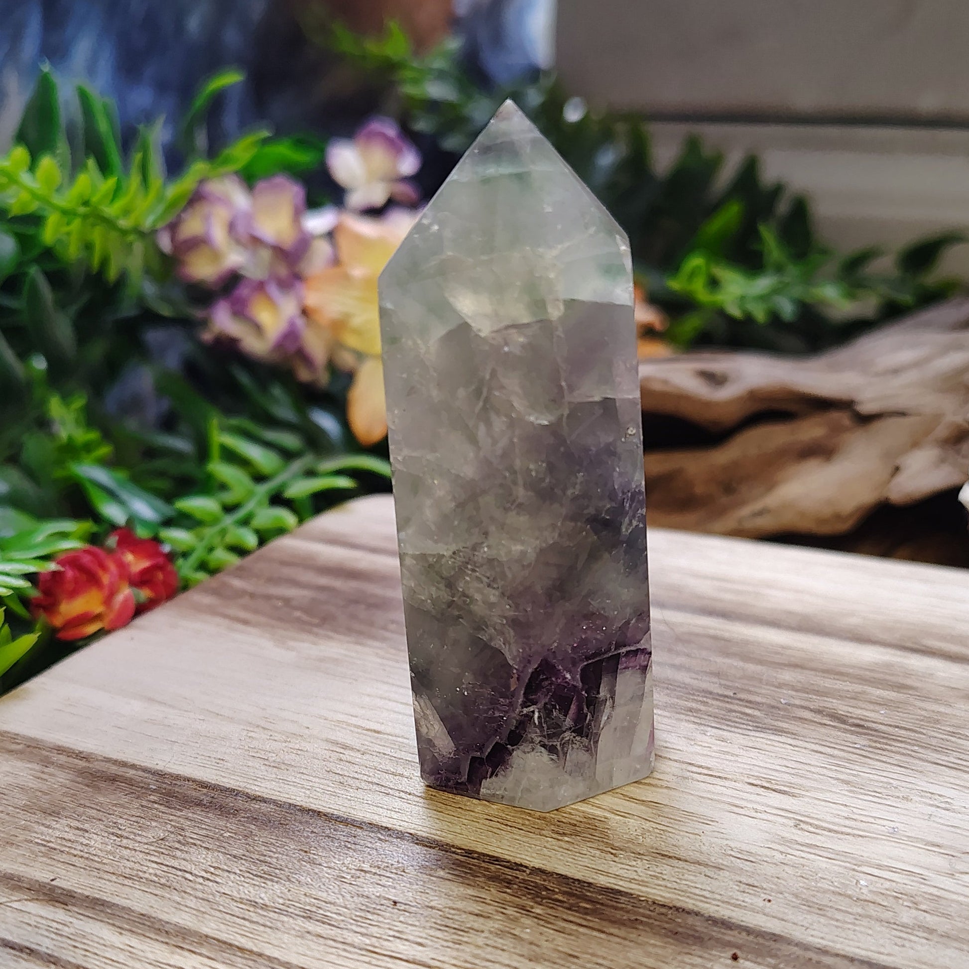 Crystal on a wooden surface with greenery and flowers in the background