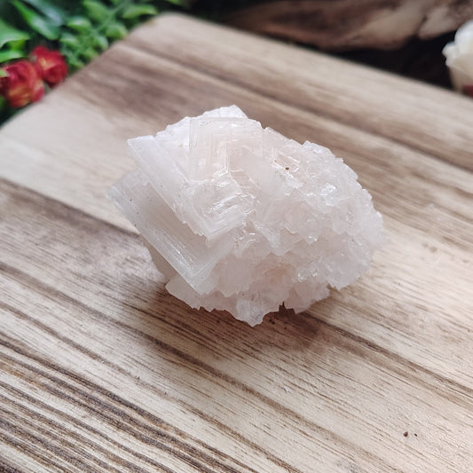 Crystal on a wooden board with greenery and fabric in the background