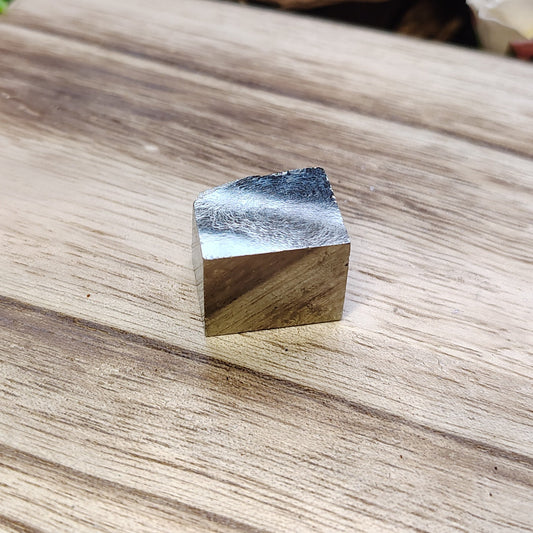pyrite cube on a wooden surface with natural elements in the background