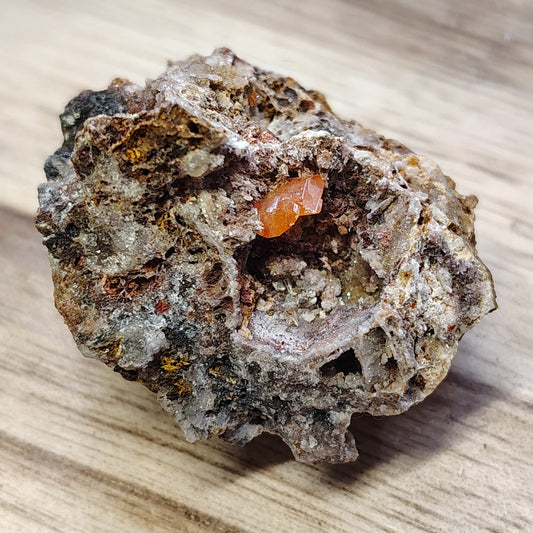 Mineral sample on a wooden surface with greenery in the background