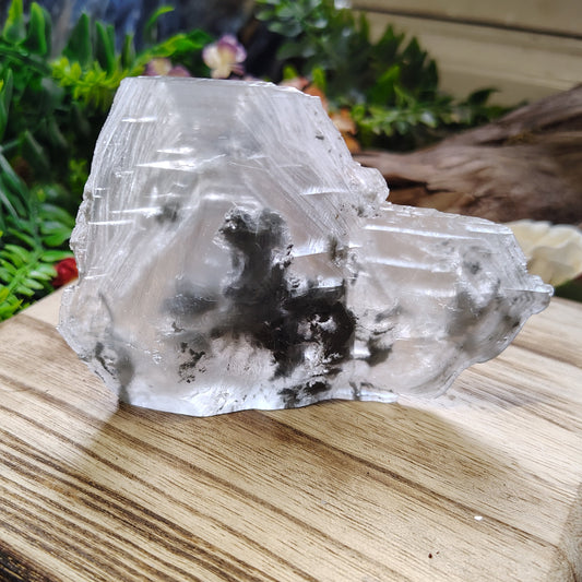 Clear crystal on a wooden stand with greenery in the background
