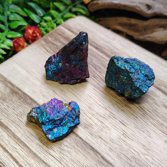 Three colorful crystals on a wooden surface with a natural background
