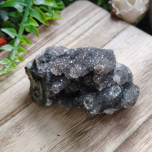 Mineral specimen on a wooden surface with flowers and plants in the background