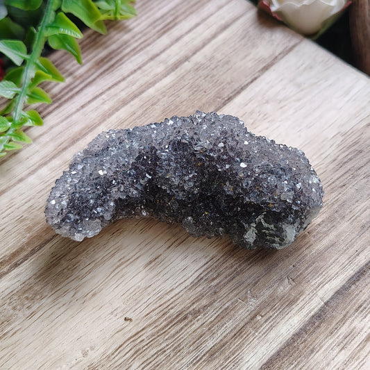 Black crystal on a wooden cutting board with decorative plants and flowers.