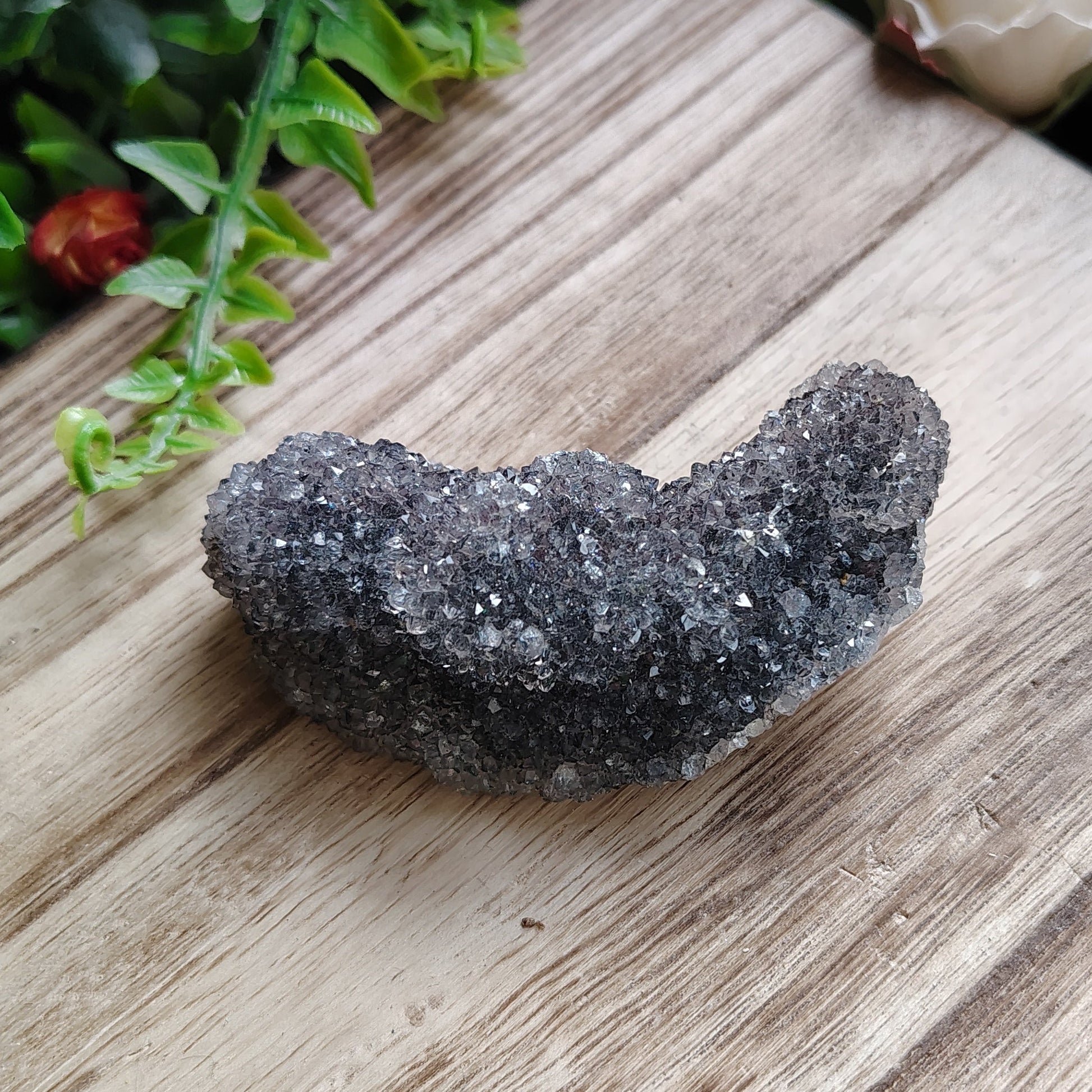 Black stone on a wooden surface with greenery around