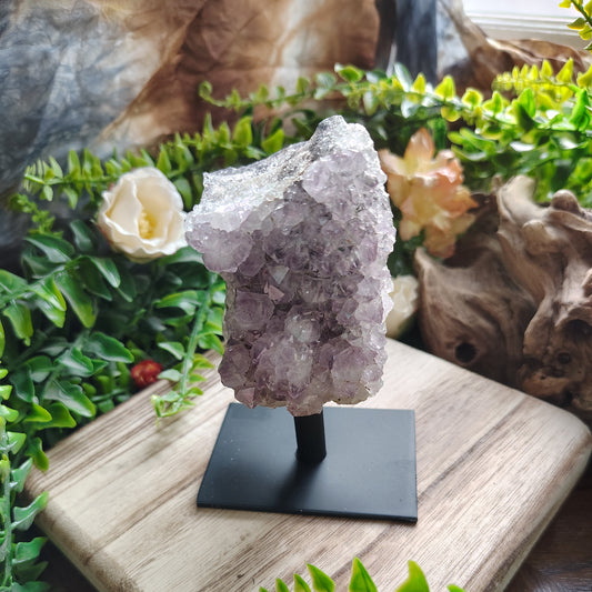 Decorative crystal on a stand with greenery and a stone in the background