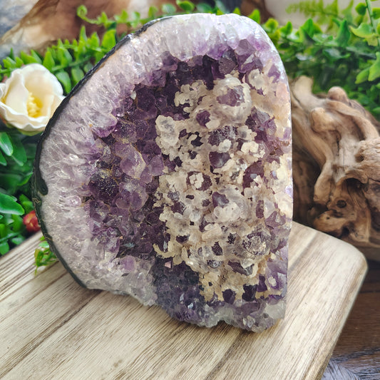 Amethyst crystal on a wooden surface with greenery