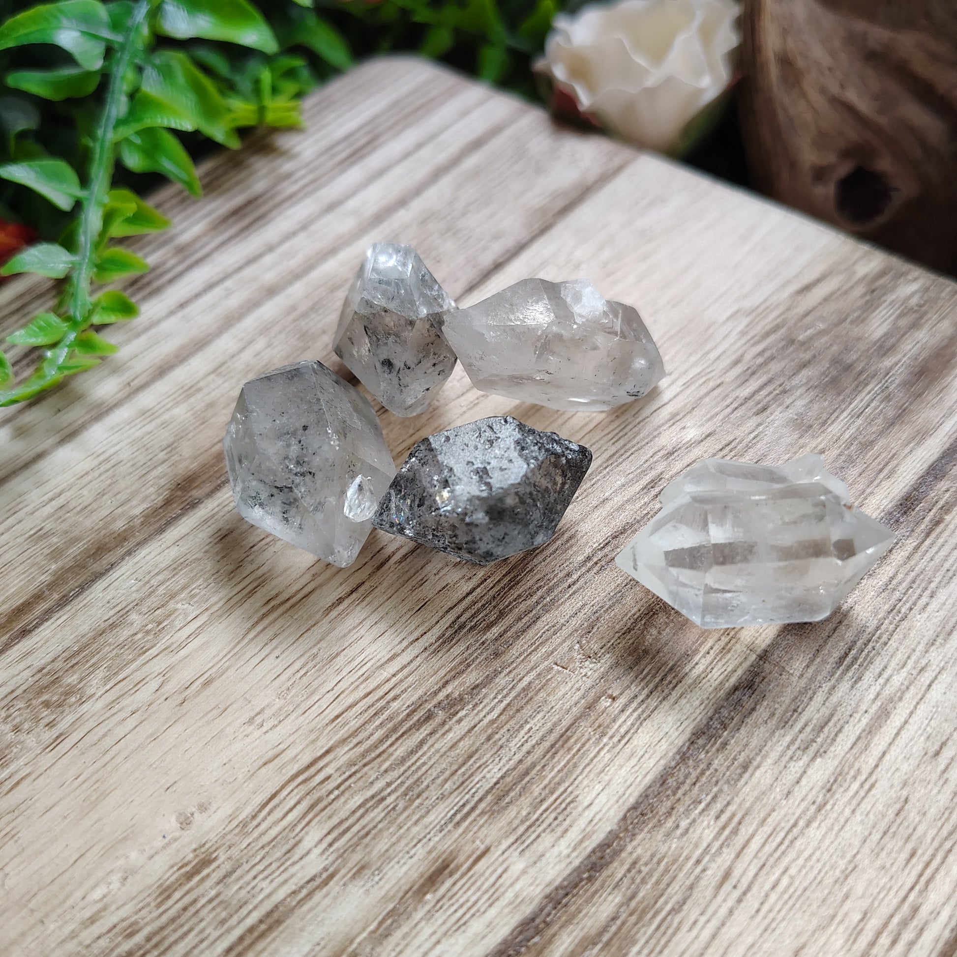 Crystal rocks on a wooden surface with plants around