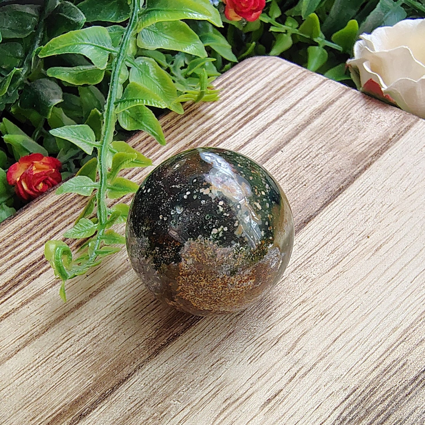 Decorative stone on a wooden board with flowers and greenery