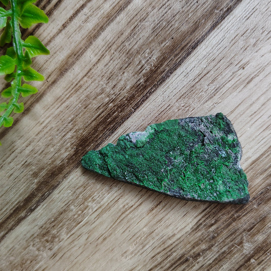 Green mineral stone on a wooden surface with green leaves