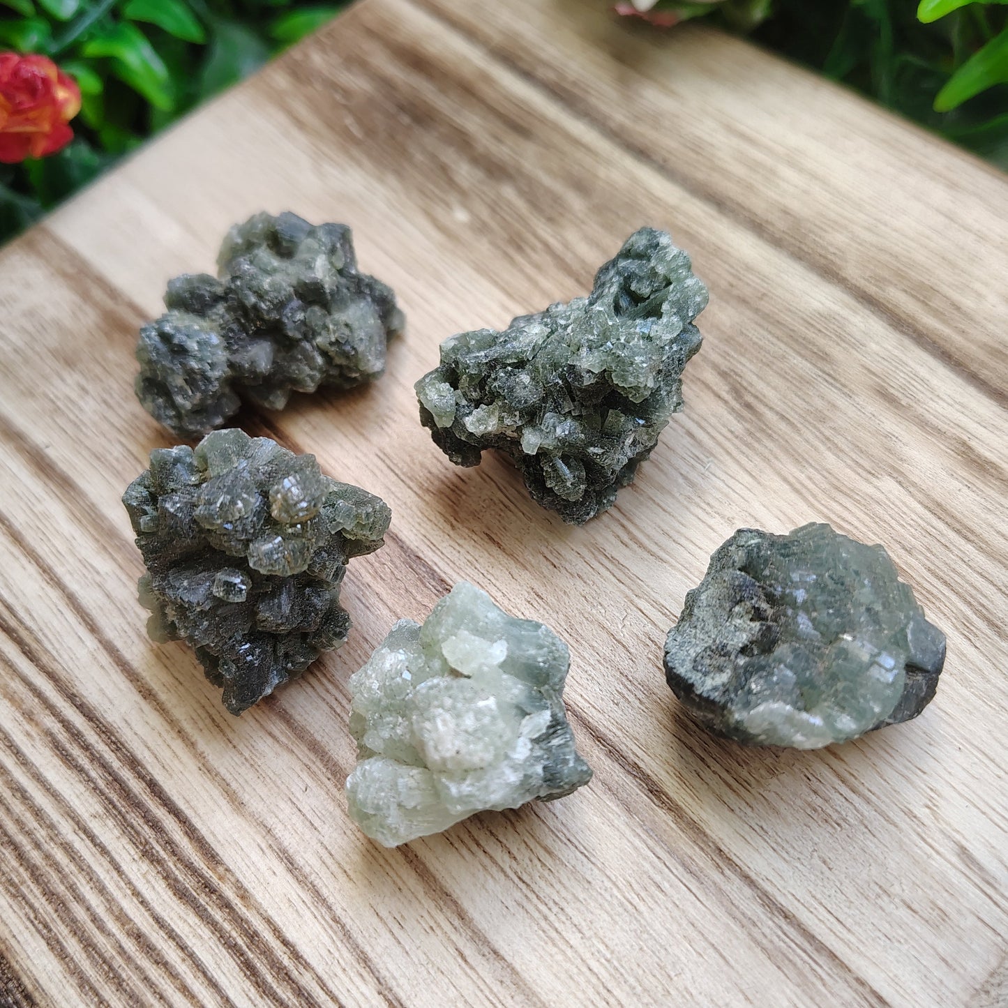 Green crystals on a wooden surface with flowers in the background