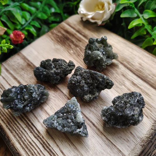 Mineral specimens on a wooden board with greenery in the background