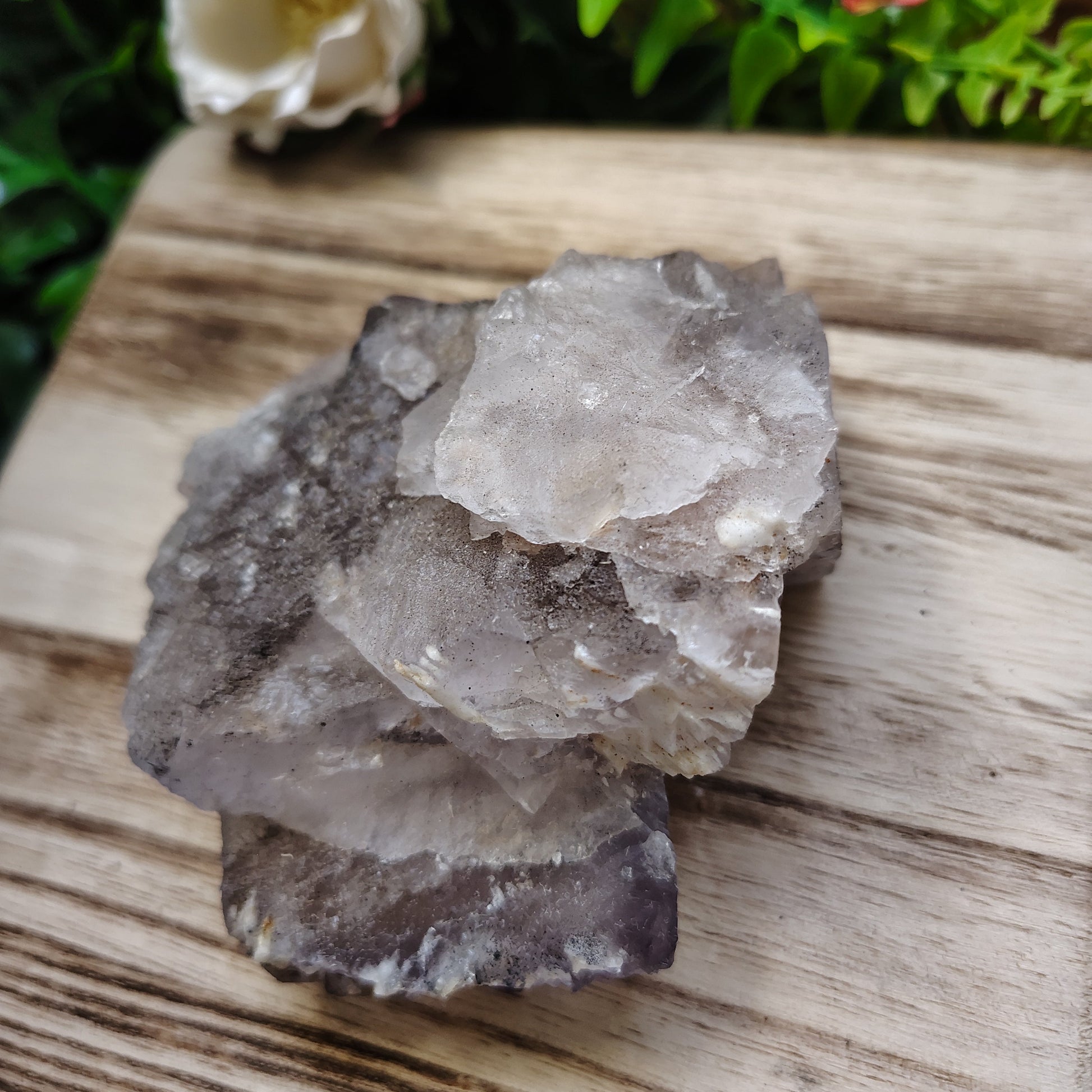 Crystal rock on a wooden surface with greenery in the background