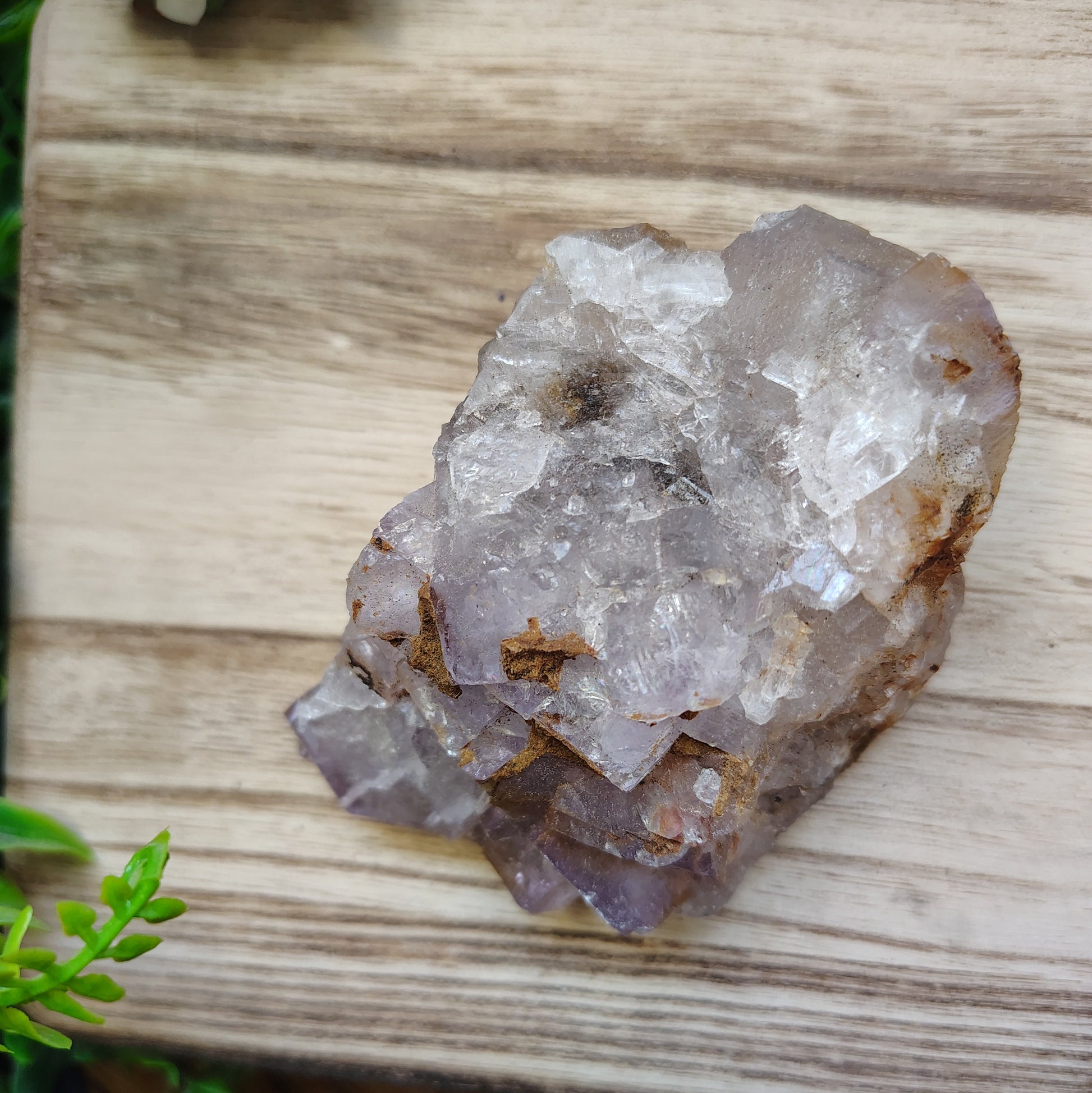 Crystal rock on a wooden surface with greenery around