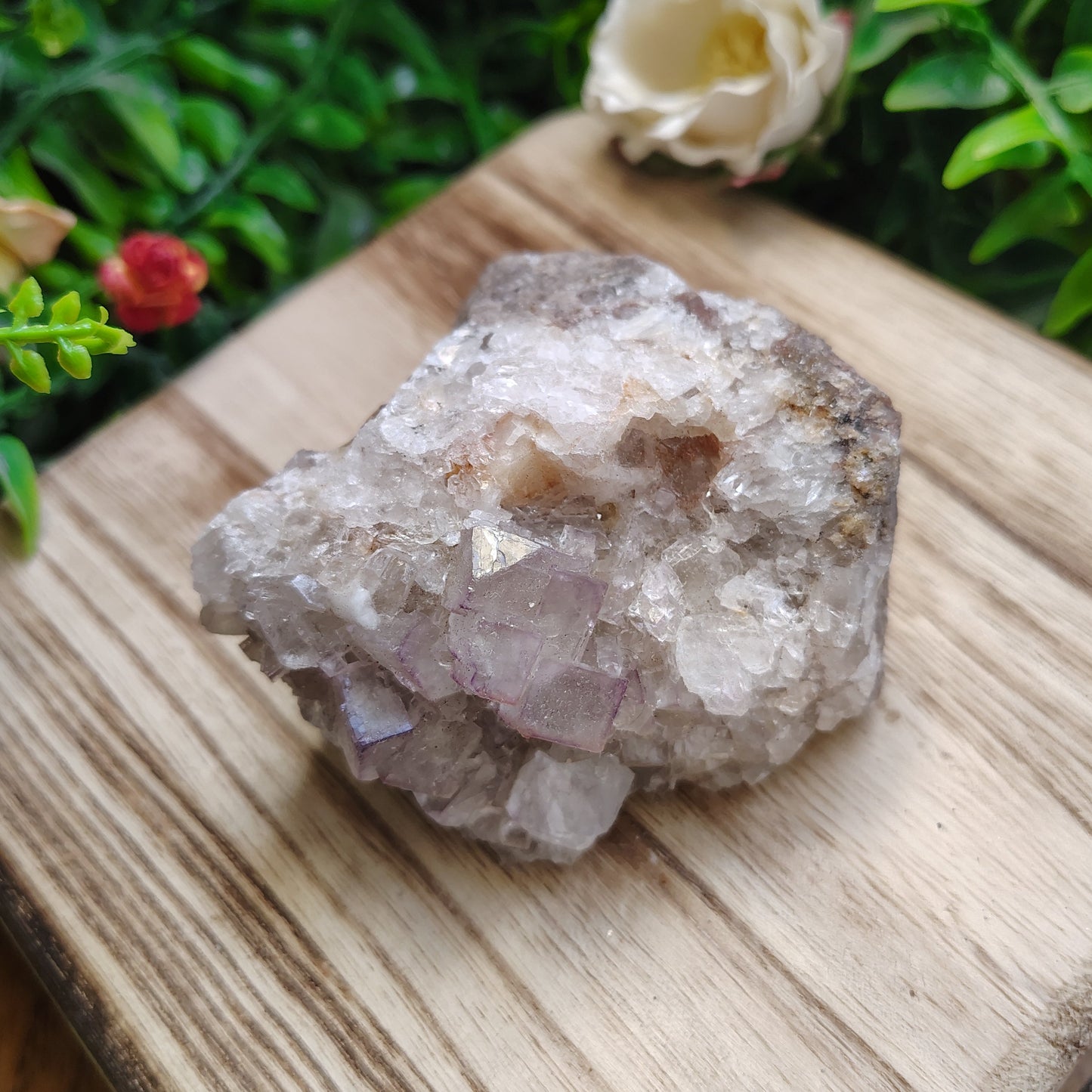 Crystal rock on a wooden surface with greenery and flowers in the background
