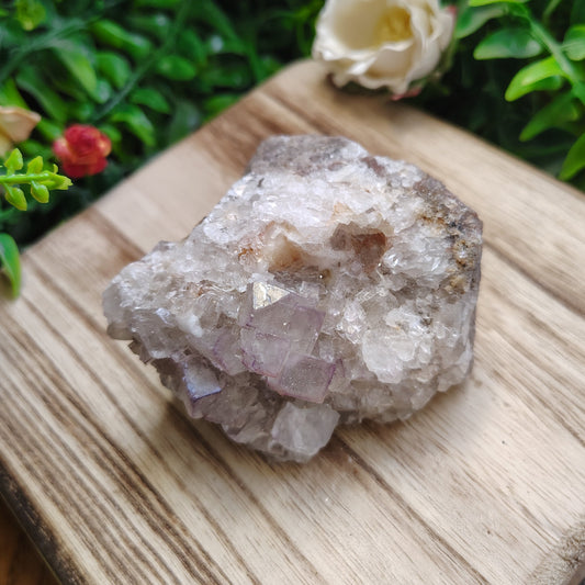 Crystal rock on a wooden surface with greenery and flowers in the background