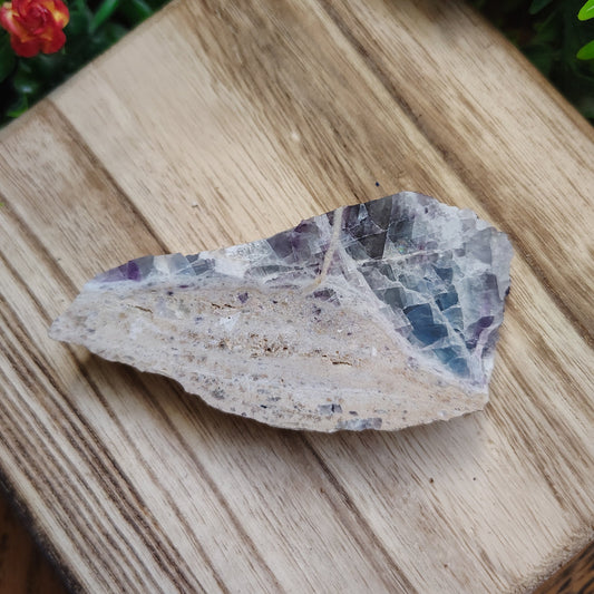 Crystal rock on a wooden surface with flowers and greenery around