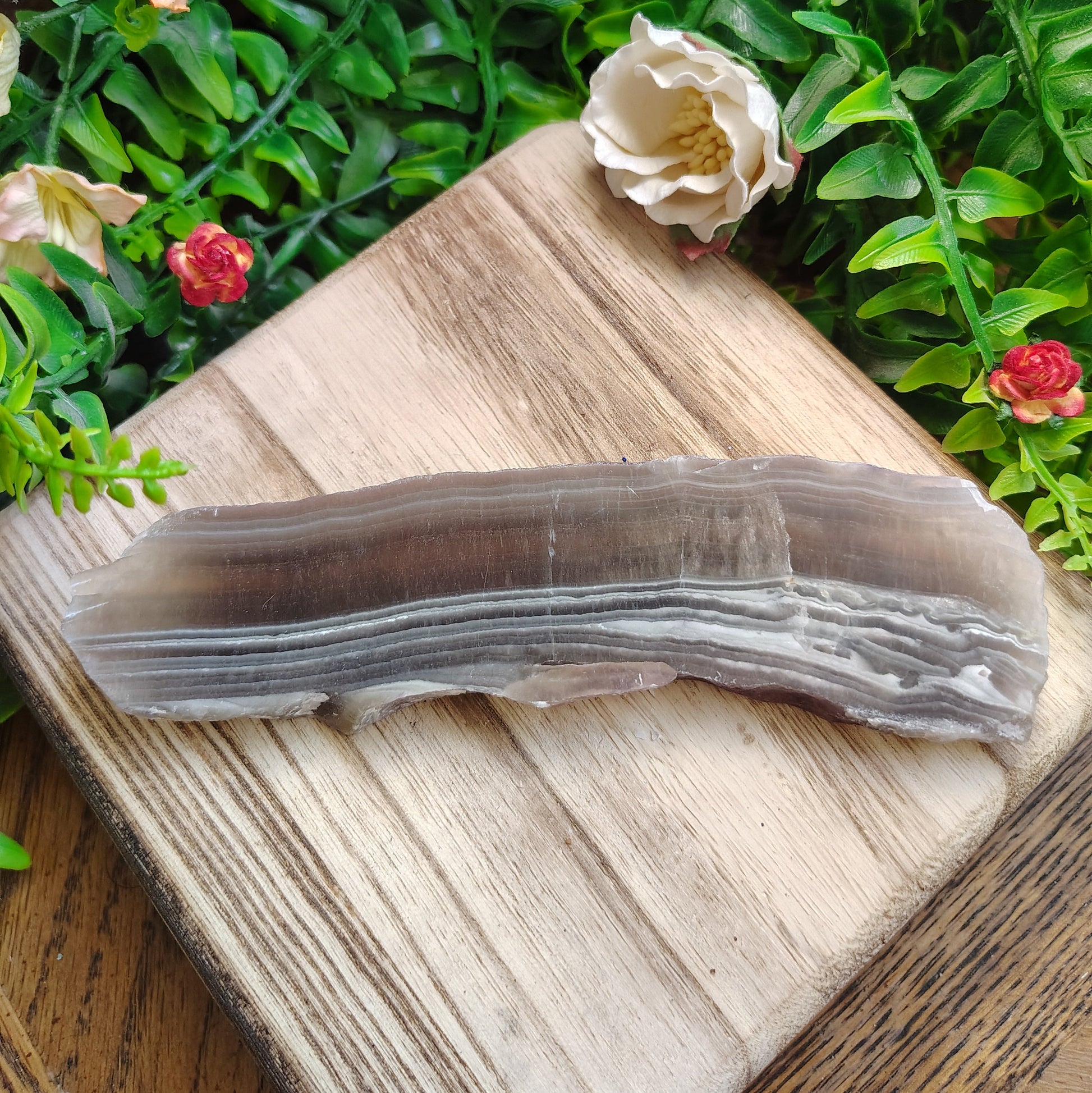 Sliced fluorite stone on a wooden board with flowers and greenery in the background