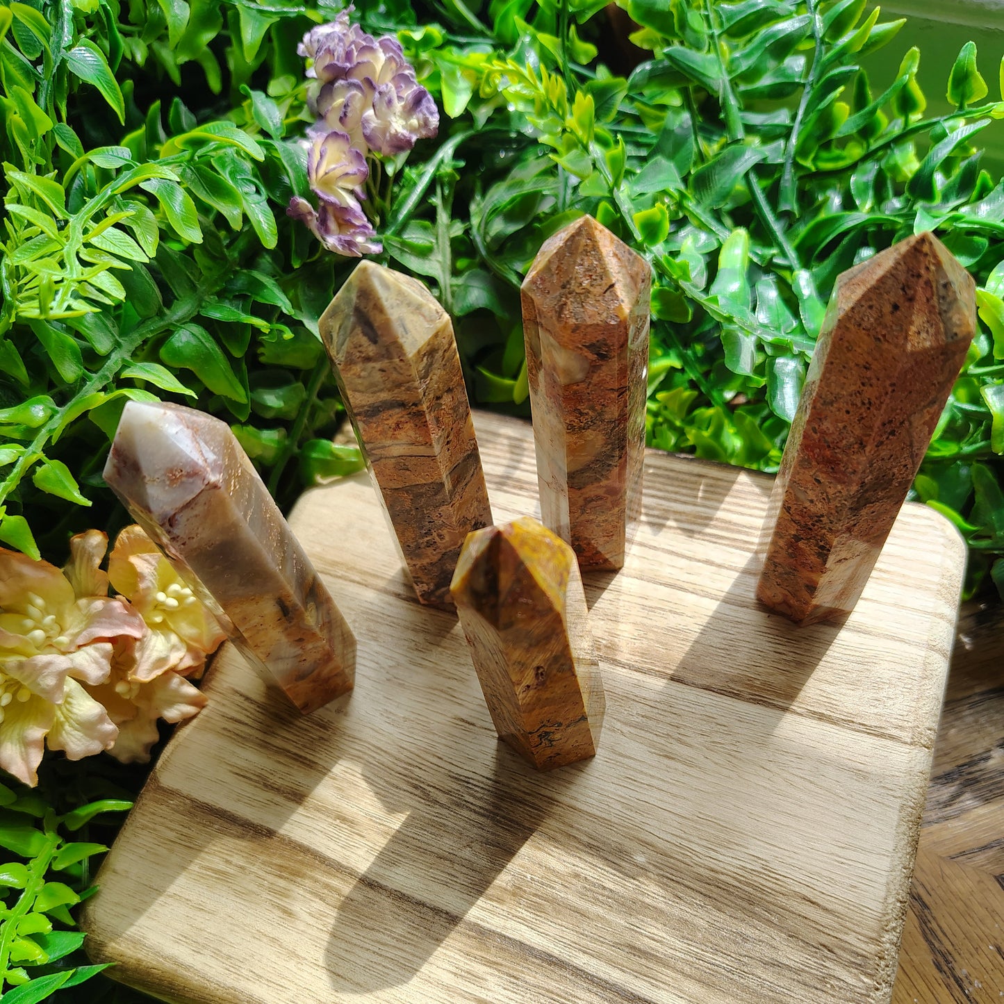 Wooden crystal holder with crystals on a green leafy background