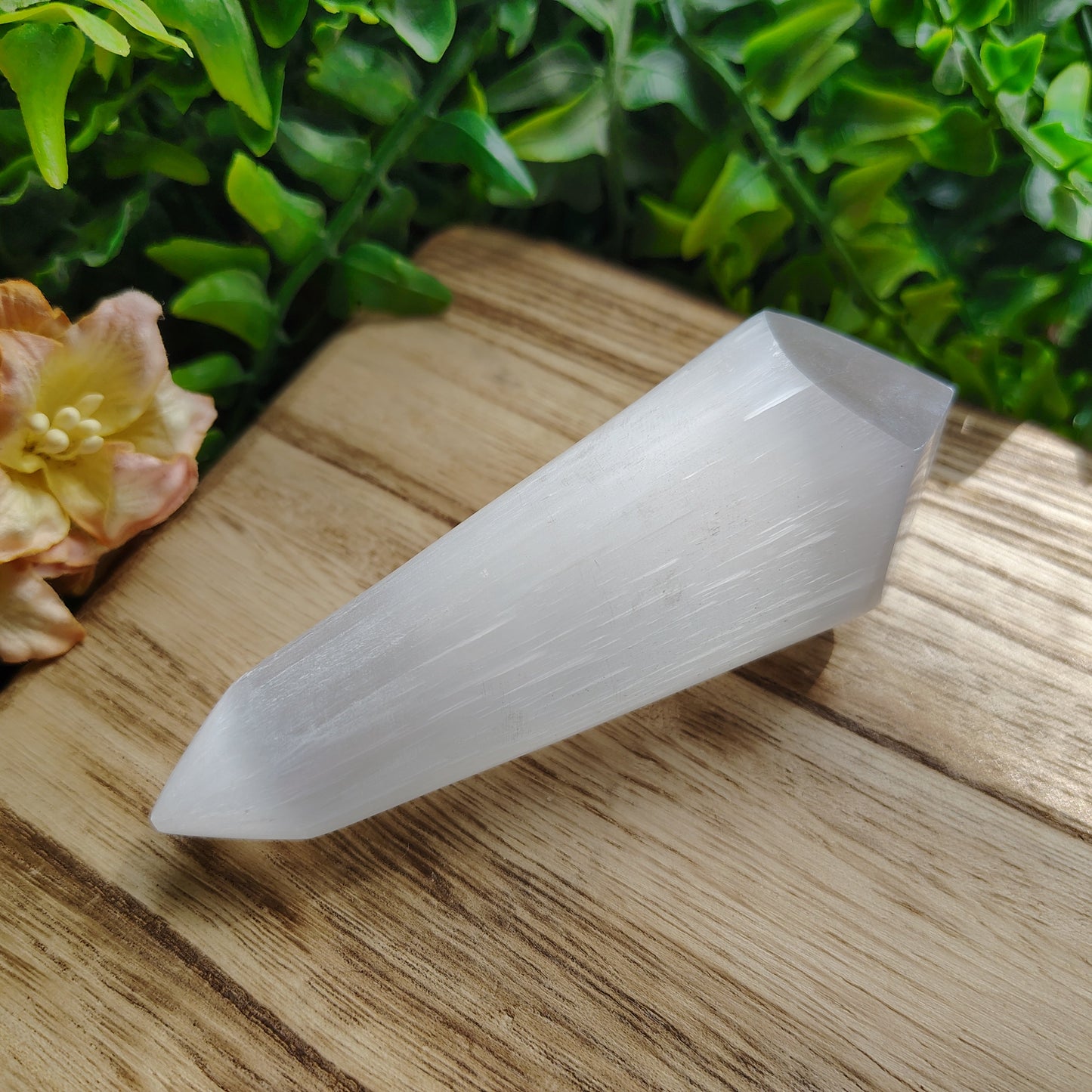 Crystal on a wooden surface with greenery and flowers in the background