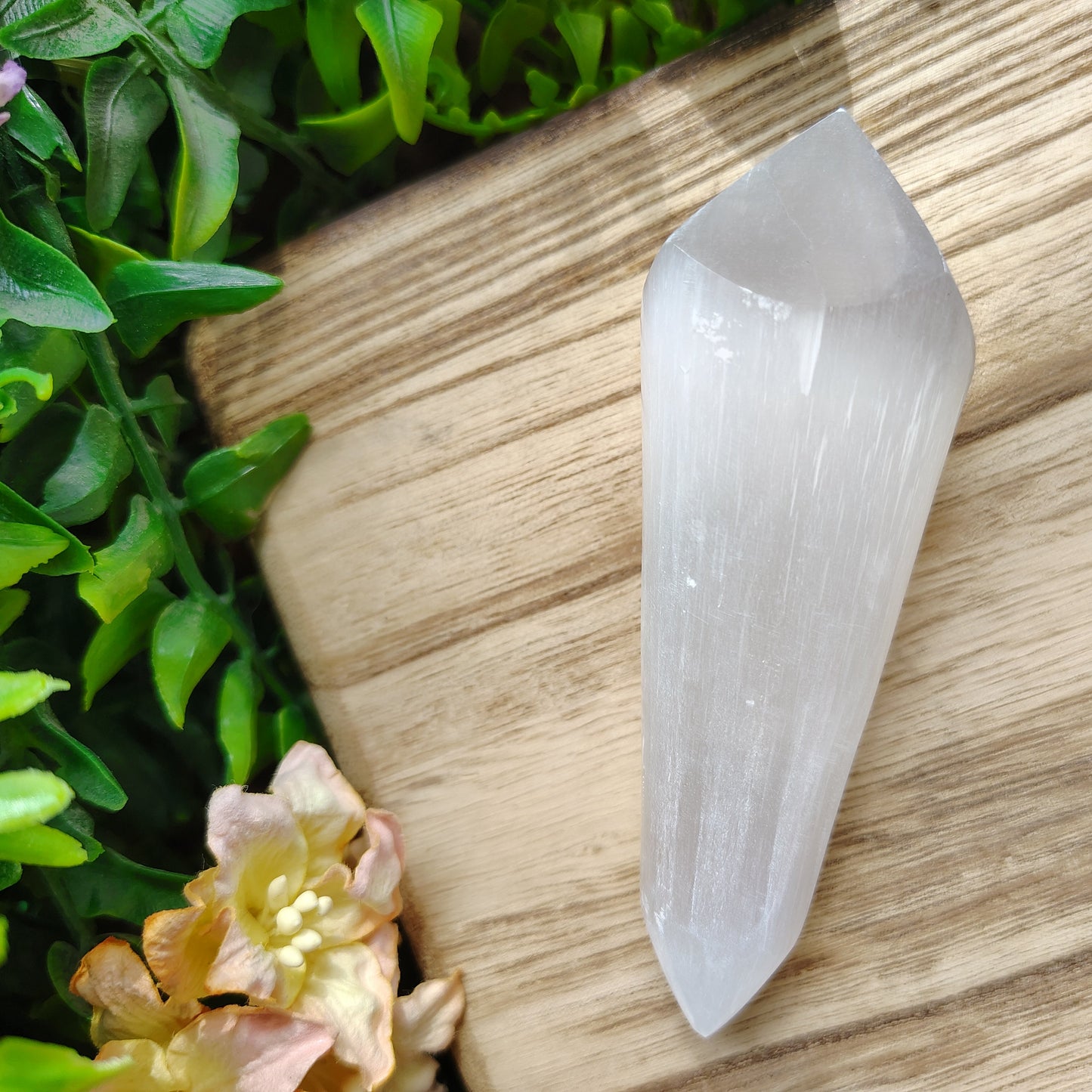 Clear crystal on a wooden surface with greenery and flowers