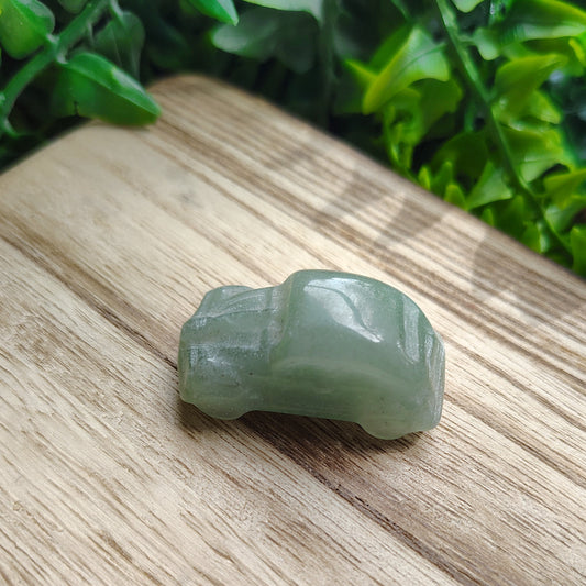 Green stone on a wooden surface with greenery in the background