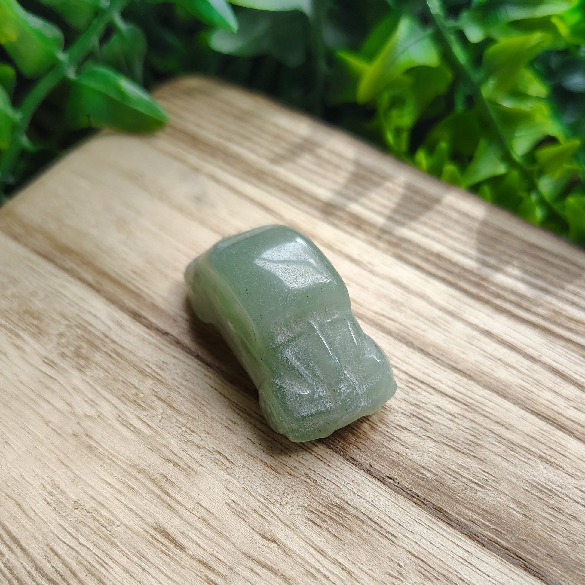 Green stone on a wooden surface with greenery in the background