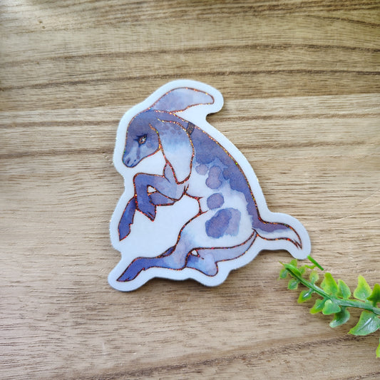 Sticker of a stylized goat on a wooden surface with greenery around